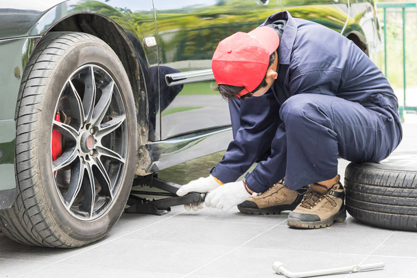 Mekaanikko korvaa rengasmutterit vaihtamalla renkaat ajoneuvoon
 - Valokuva, kuva