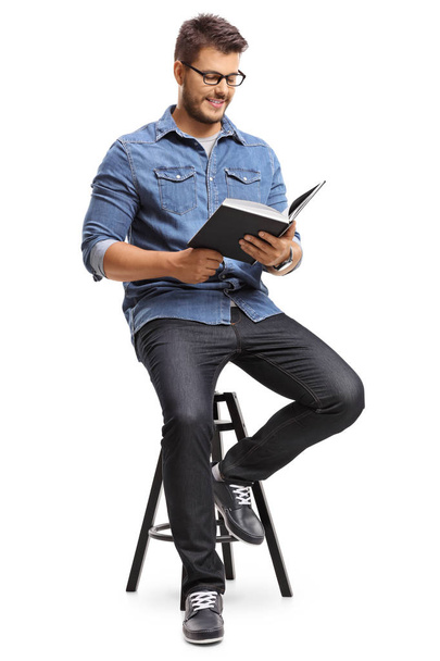 Guy sitting on a chair and reading a book - Foto, Bild