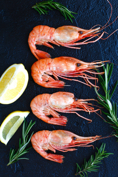Shrimps with lemon and rosemary on a dark background - Photo, image
