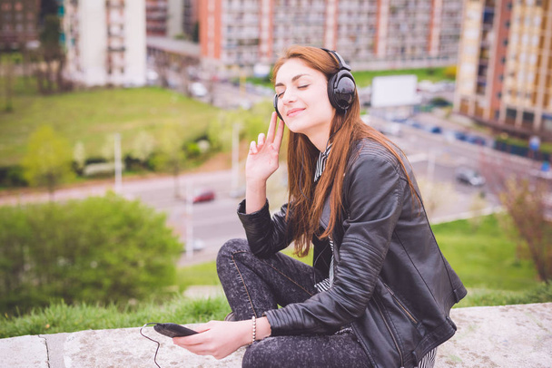 tyttö kuuntelee musiikkia puistossa kaupungissa
  - Valokuva, kuva