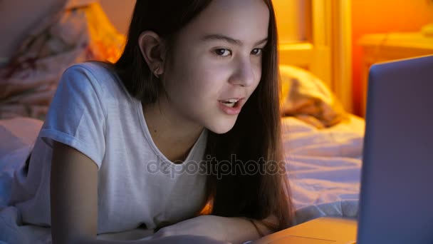 Closeup footage of beautiful girl having night talk via video messenger on laptop at bedroom - Felvétel, videó