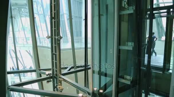 Modern metal construction of glass elevator shaft with lift going up and down - Πλάνα, βίντεο