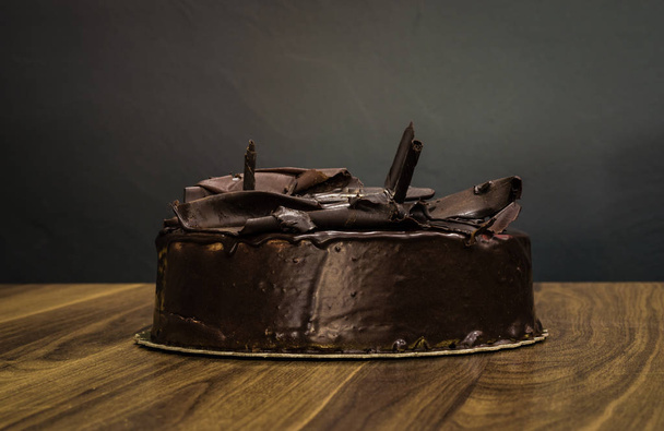 Heerlijke romige hele donkere chocolade cake op donkere achtergrond - Foto, afbeelding