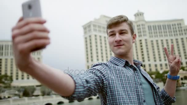 Young attractive man is taking a picture of himself while showing a victory sign - Záběry, video