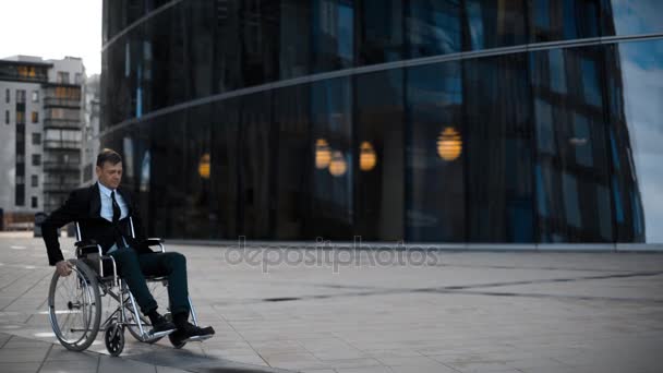 Инвалидный бизнесмен катается на инвалидной коляске рядом с бизнес-центром
 - Кадры, видео