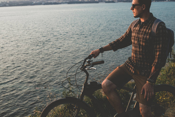Young Man Standing With Bike On Coast And Enjoying View of Nature Sunset Vacation Traveling Relaxation Resting Concept - Zdjęcie, obraz