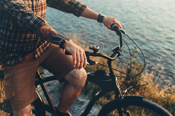 Unrecognizable Young Man Standing With Bike On Coast And Enjoying View of Nature Sunset Vacation Traveling Relaxation Resting Concept - Photo, Image