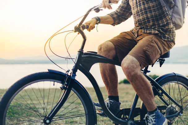 Unrecognizable Young Man Is Cycling Along The Shore Against The Backdrop Of The Sunset Vacation Holiday Activity Concept - Photo, Image