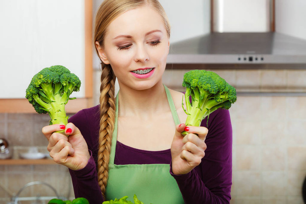 Woman in kitchen with green fresh broccoli - Photo, Image