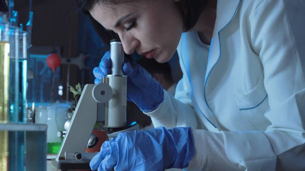 Молодая женщина-ученый смотрит под микроскоп
 - Фото, изображение