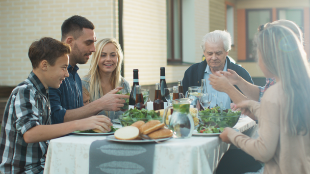 Groupe de personnes de race mixte qui s'amusent, communiquent et mangent au dîner familial en plein air
 - Séquence, vidéo