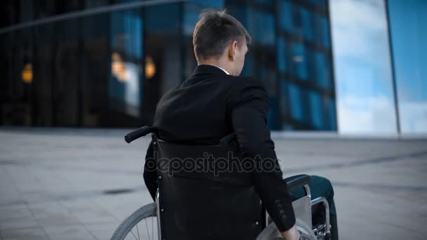 Disabled handicapped businessman unfolds on wheelchair outdoor - Video