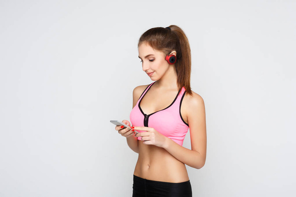 Fitness ragazza in cuffia scegliere la musica sul telefono
 - Foto, immagini