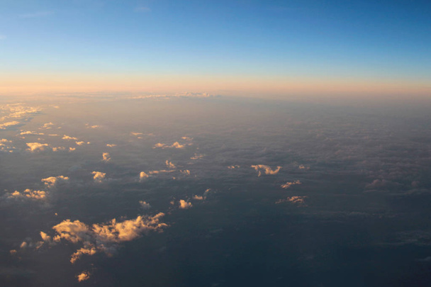 Spectaculair uitzicht van een zonsondergang boven de wolken uit vliegtuig wind - Foto, afbeelding