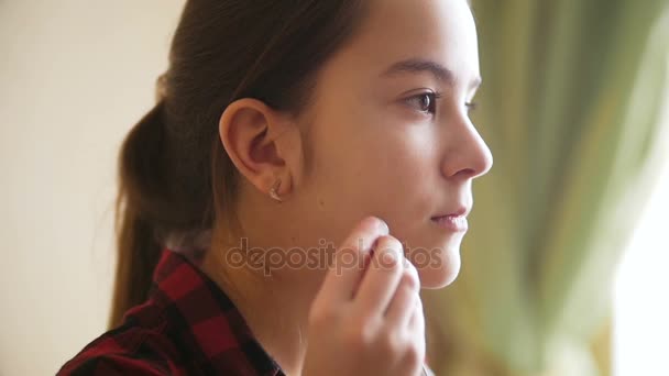 Замедленная съемка грустной девочки-подростка, засовывающей наушники в уши и выглядывающей в окно
 - Кадры, видео
