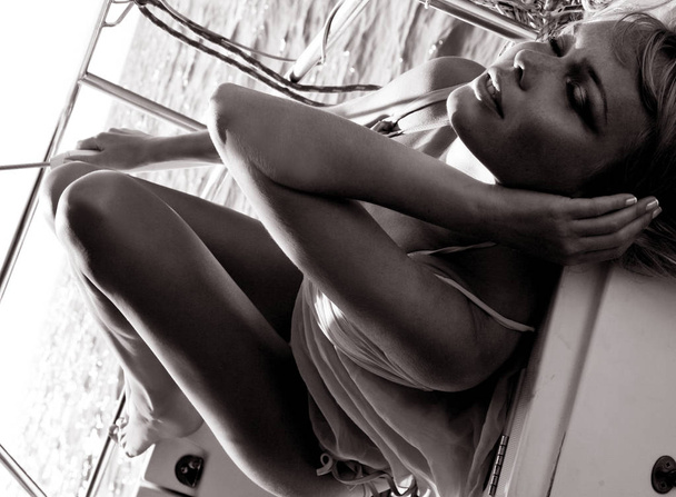 Beautiful young blond female model sunbathing on a yacht in the sea - Photo, image