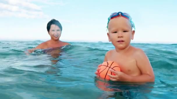 poika ja äiti pelaa palloa meressä hidastettuna
 - Materiaali, video