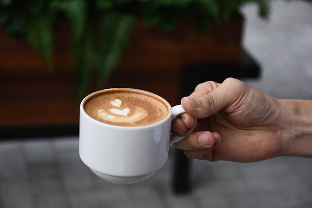 Hand holding hot cup of coffee - Foto, afbeelding