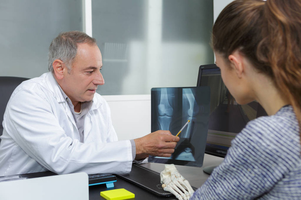 Dokter toont röntgenresultaten aan patiënt - Foto, afbeelding