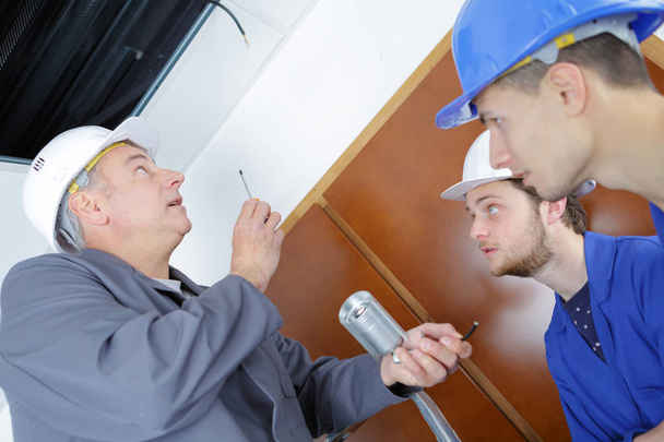 electrician repairman and apprentices fixing air conditioning in a house - Photo, Image