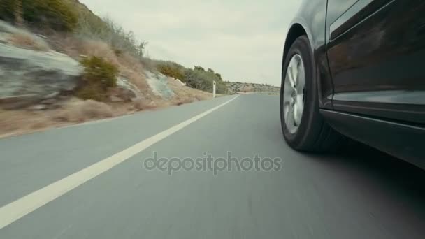 Bewegung des Autos auf einer Straße in hügeligem Gelände. Autoräder bewegen sich mit hoher Geschwindigkeit auf glattem Asphalt - Filmmaterial, Video