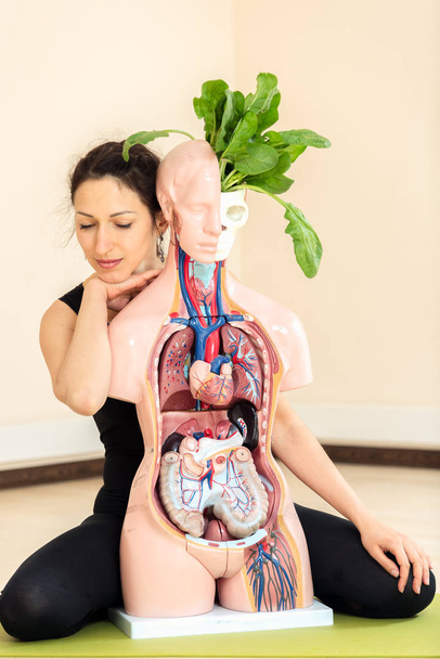 A yoga coach sits next to a medical dummy - Foto, Imagen