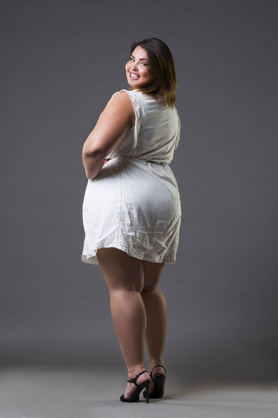 Happy plus size fashion model in casual clothes, fat woman on gray background, overweight female body - 写真・画像