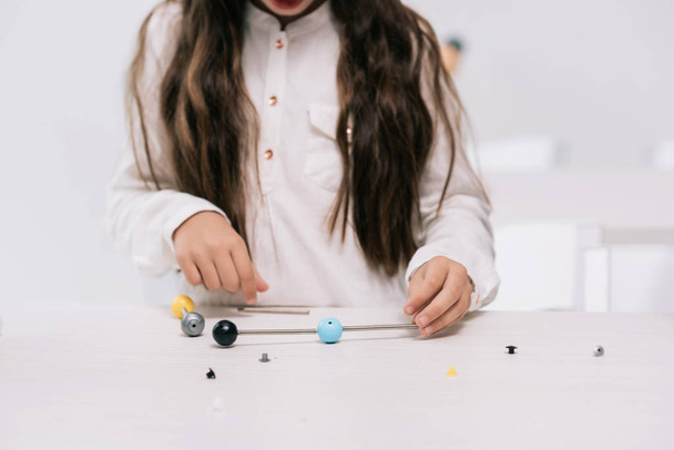 Koulutyttö molekyylimallilla
 - Valokuva, kuva