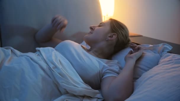 4 k felvétel, fiatal nő kikapcsolása fény a hálószobában, mielőtt aludni - Felvétel, videó