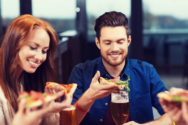 friends eating pizza with beer at restaurant - Foto, imagen
