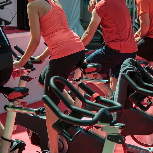 Erkek ve kız spor salonunda Grup: egzersiz bisikletleri iplik ile - Fotoğraf, Görsel