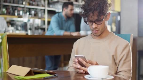Ισπανόφωνος εθνικότητα νεαρός χρησιμοποιώντας το κινητό τηλέφωνο στο άνετο κατάστημα καφέ. - Πλάνα, βίντεο