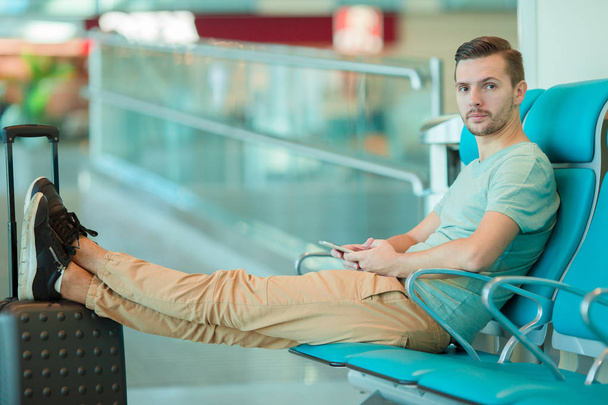 若い男が着陸を待っている空港ラウンジで - 写真・画像