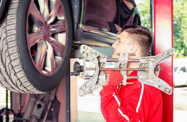 Mécanicien automobile tenant une pièce d'équipement dans un travail automobile
 - Photo, image