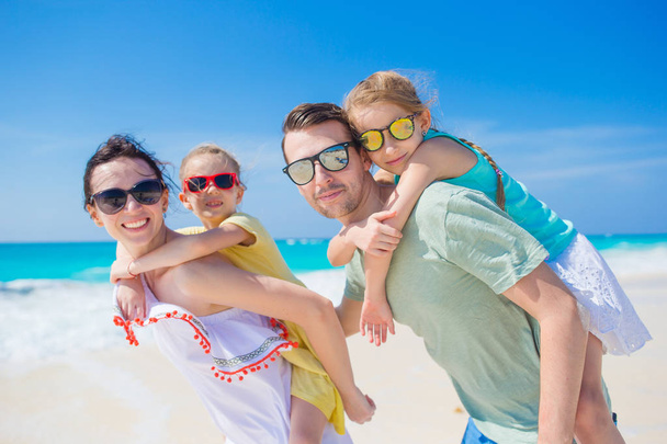 Happy beautiful family of four on a tropical beach. Parents and kids background seashore on beach vacation - Fotografie, Obrázek