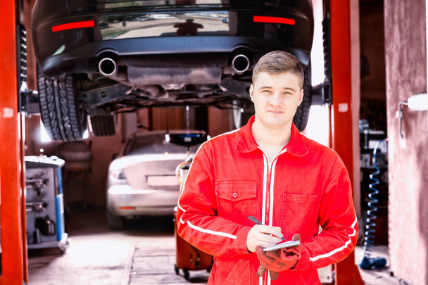 Handsome male motor mechanic standing making notes - Photo, Image