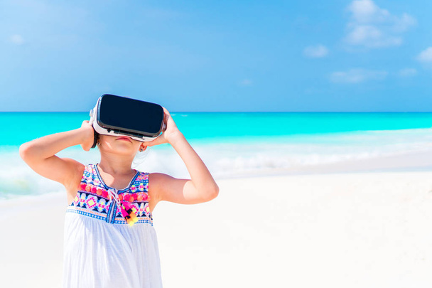 Meisje met behulp van Vr-VR bril. Schattig kind kijken naar de virtuele bril op het witte strand - Foto, afbeelding