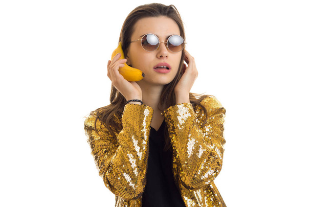 young stylish woman in golden jacket with banan - 写真・画像