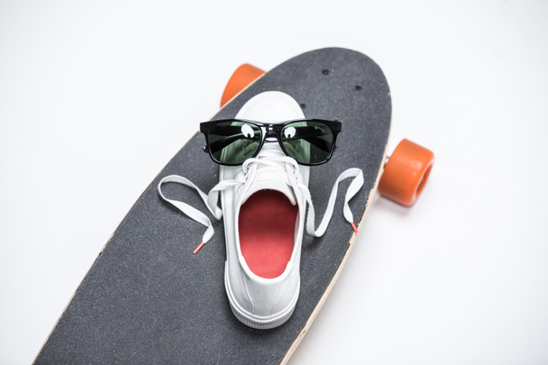 zapatillas de deporte y gafas de sol en el monopatín
 - Foto, Imagen