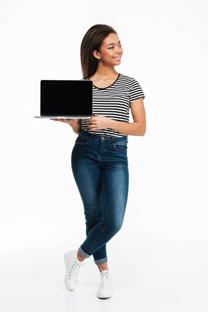 Smiling casual african woman standing and holding blank screen laptop - Фото, зображення