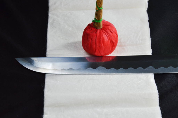 Katana Japanilainen miekka terä ja punainen pakata puhtaammalla liinalla
 - Valokuva, kuva