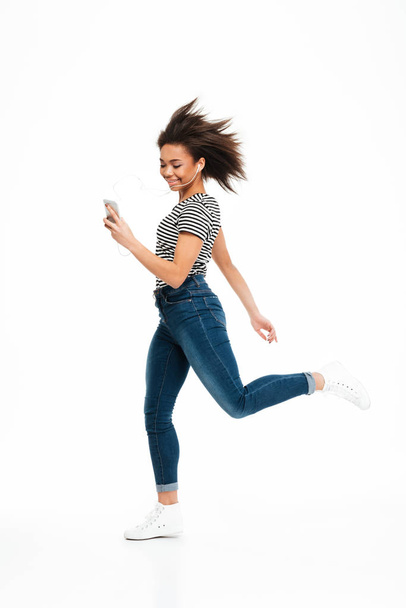 Full length portrait of a happy carefree african girl jumping - Photo, image