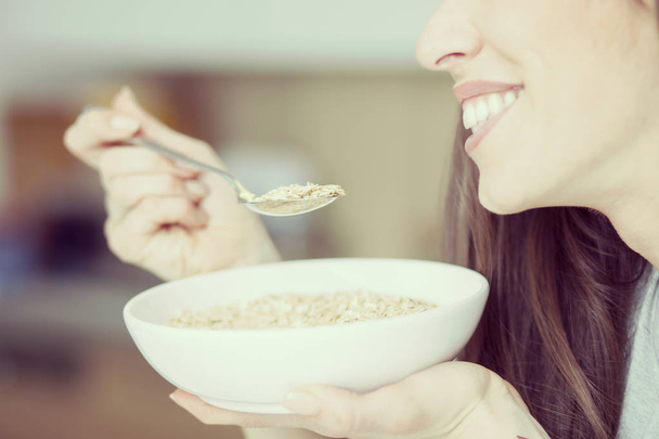 Beautiful young  woman breakfast cereals in the kitchen - Foto, afbeelding