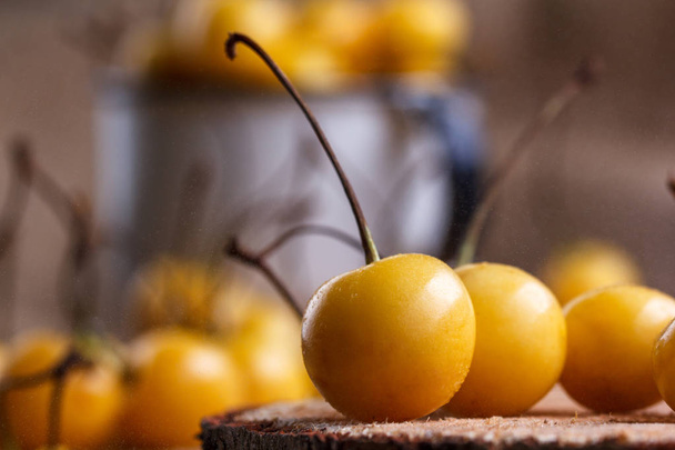 Yellow cherry in a rustic style on a wooden background. Berries of ripe fresh cherries in a cup. - Photo, image