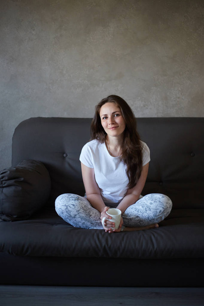Woman sits on couch and drinking tea - Valokuva, kuva