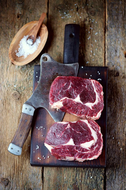 Steak de bœuf cru frais avec sel de mer sur une planche de service sur un vieux fond en bois
. - Photo, image