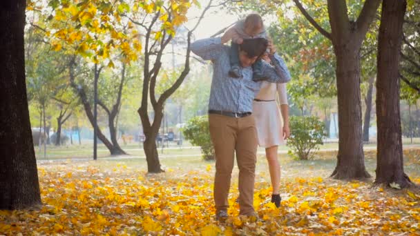 Imágenes en cámara lenta de feliz madre y padre jugando con su bebé en el parque de otoño
 - Metraje, vídeo