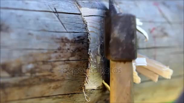 Het maken van een groef in de balk voor de vaststelling van de lag, waarnaar de vloer is gepland met behulp van een bijl handmatig, Rusland. - Video