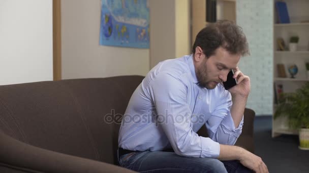 Upset male sitting at home and chatting with ex-wife on smartphone, problems - Filmmaterial, Video