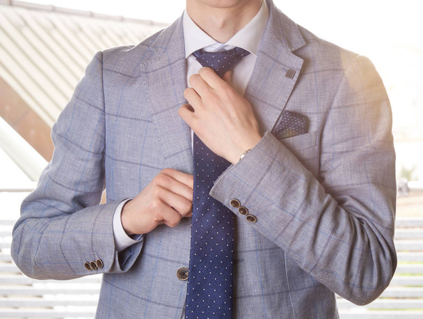 Unerkennbarer Geschäftsmann, der sich für die Arbeit anzieht und seine Krawatte justiert. weiche Farben mit einem Linsenschlag. - Foto, Bild
